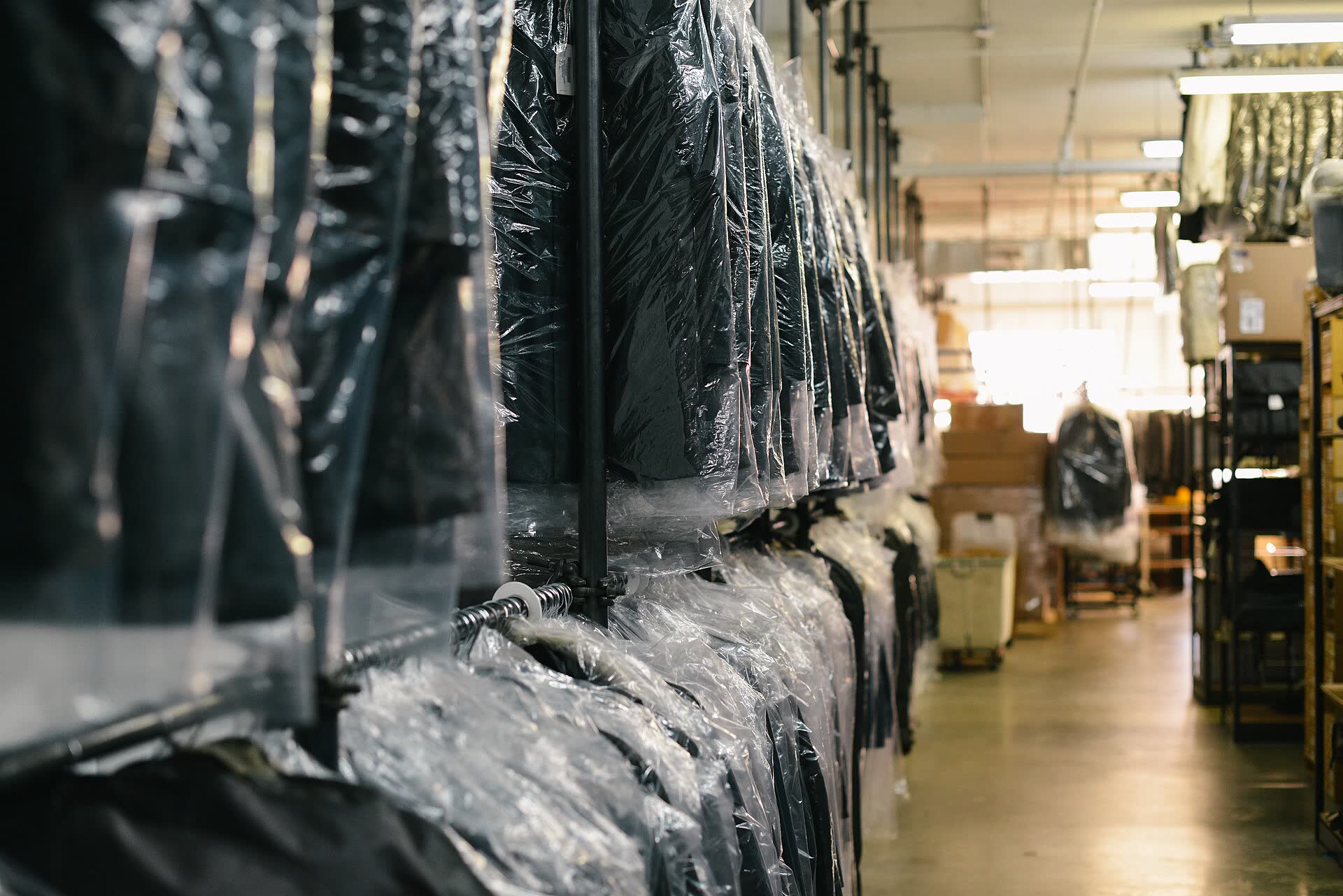 Una lunga fila di capi puliti appesi nelle custodie di plastica, nel retro di una tintoria